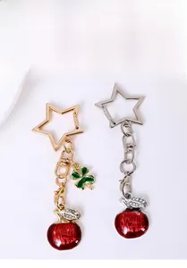 Detail view of red apple and clover charms on star-shaped golden and silver keychains