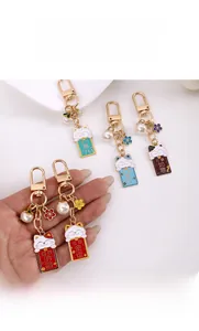 Close-up of cute enamel lucky cat keychains with pearls and gold metal lobster clasps