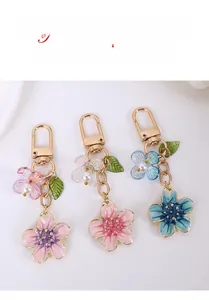 Close-up of cherry blossom keychains with enamel petals, pearls and gold snap hooks