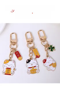 Détail de porte-clés chat porte-bonheur doré avec finition émail et étiquettes