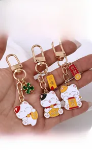 Vue détaillée de trois porte-clés Maneki Neko en alliage doré avec breloques en émail coloré