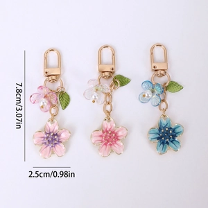 Three minimalist cherry blossom pendant keychains with pink and blue gradient petals
