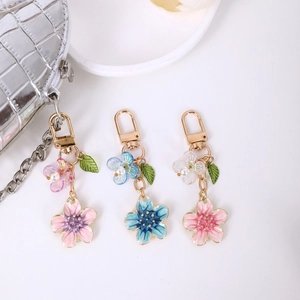 Minimalist cherry blossom pendants with pearls and gold clips on a silver handbag