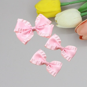 Three elegant pink ruffled bow hair clips arranged with tulips on a clean background