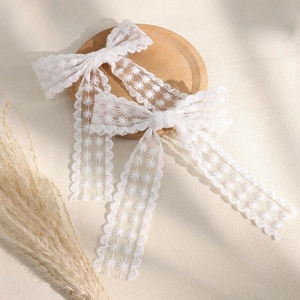 Dettaglio di fermagli per capelli con fiocchi in pizzo bianco e ricami floreali eleganti