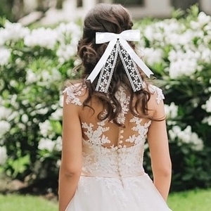 Eleganter weißer Spitzenbogen-Haarclip mit langen Bändern getragen von einem Modell