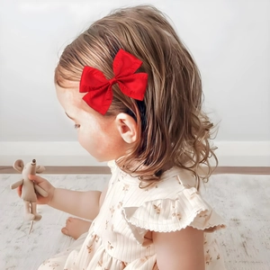 Elegant red pleated bow hair clip accessory worn by a little girl for a stylish look