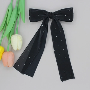 Detail of elegant black double-layered bow hair clip with sparkling rhinestones and long ribbons