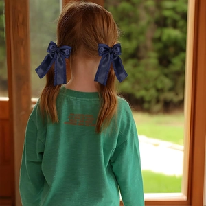 Sweet navy blue satin bow hair clips for girls shown on a model with red hair