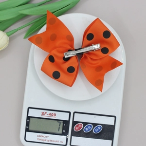 Mesure du poids de 7g montrant un nœud papillon orange à pois en ruban gros-grain