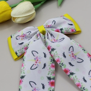 Detail of white grosgrain bow hair clip with unicorn prints and yellow trim accents