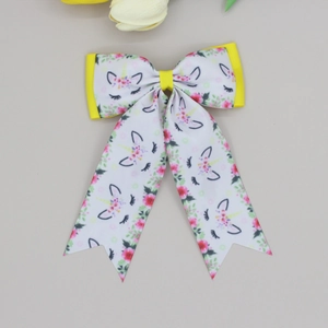 Detailed macro view of white unicorn print ribbon bow hair clip with yellow accents