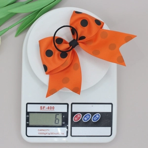 Détail d'un nœud papillon orange à pois pesant 6g sur une balance numérique