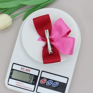 Detail van de rood met roze geribbelde strik haarklem die 9 gram weegt op schaal