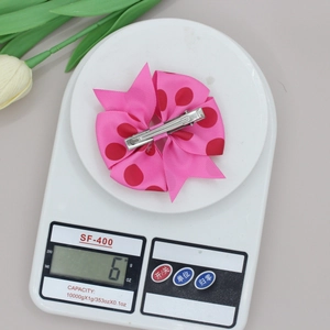 Detail van roze geribbelde strik haarclip met rode stippen en een gewicht van 6 gram
