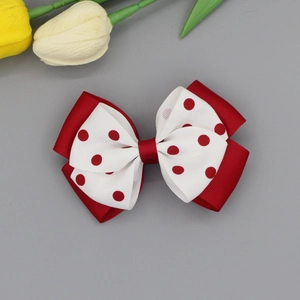 Close-up of double-layered red and polka dot bow hair clip for girls with a ribbon center