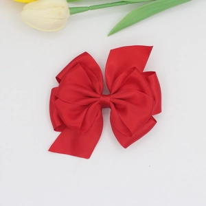Close-up of large red layered ribbon bow hair clip with elegant satin texture