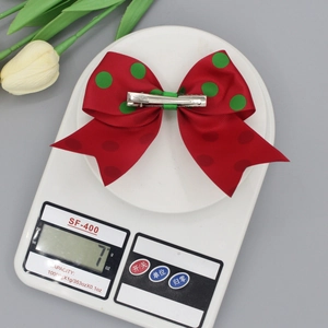 Barrette nœud papillon rouge à pois verts pesant 7g sur une balance de précision