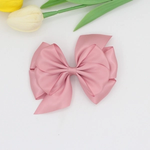 Detail view of multi-layered pink satin bow hair clip with elegant silk texture