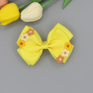 Detail of yellow ribbed ribbon hair bow with delicate handmade floral embroidery patterns