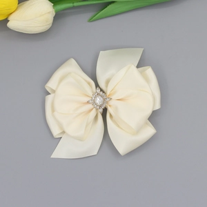 Gros plan sur la barrette nœud en satin crème avec centre orné de strass brillants