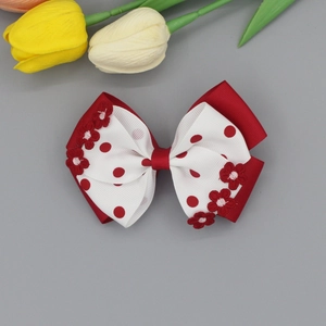 Detail of a red and white polka dot ribbon hair clip with delicate flower embroidery