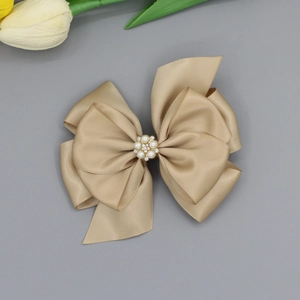 Details einer champagnerfarbenen Satin-Haarschleife mit Perlen- und Strass-Deko