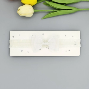 Vue détaillée du bandeau en dentelle blanche pour bébé avec nœud sur carte d'affichage