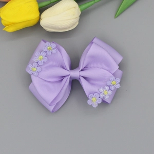 Detail showing the layered lavender ribbed ribbon bow with embroidered daisy flowers