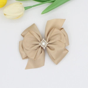 Gros plan sur la barrette nœud en satin champagne avec centre en strass et décor de tulipe