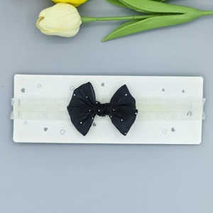 Détail du bandeau pour bébé avec un nœud noir à pois sur une carte de présentation