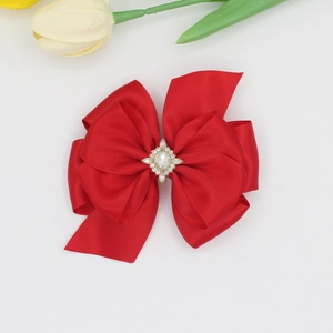 Détail d'une pince à cheveux avec nœud rouge superposé et ornement en strass brillant
