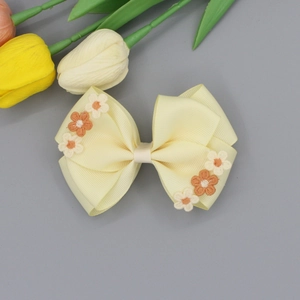 Detailed texture of yellow ribbed fabric bow hairpin with exquisite floral embroidery