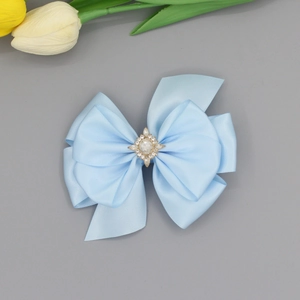 Détail d'une pince à cheveux en satin bleu clair avec cristal central et diamants