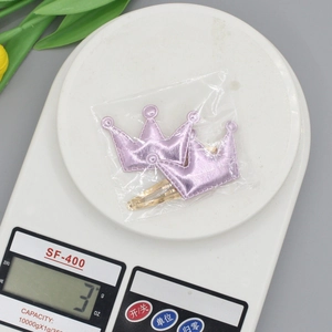 Pair of crown-shaped pink star hair clips on a scale showing 3g lightweight design
