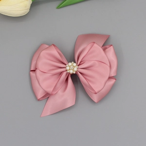 Rosa Satin-Haarspange mit Schleife, Perlen und Strasssteinen auf weichem Hintergrund