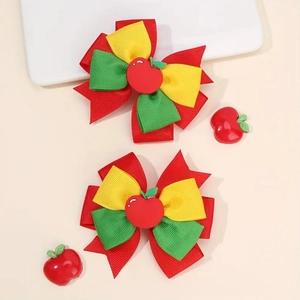 Détail de barrettes à cheveux en ruban avec motifs pommes rouges sur plateau céramique