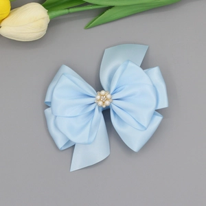 Hellblaue Satin-Haarspange mit Schleife und Perlen-Blüten-Verzierung vor grauem Hintergrund