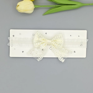 Détails de la broderie florale sur le nœud du bandeau en dentelle crème pour bébé
