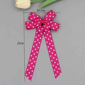 Detail of pink ribbon bow hair clip with white heart pattern showing 10.5x22cm size