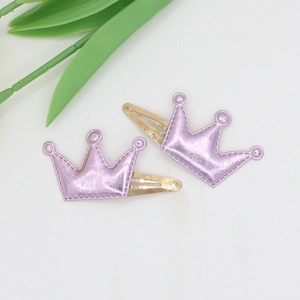 Detail of two-piece purple crown hair clips with metallic texture and gold snap clip