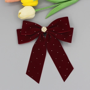 Detail of burgundy velvet bow hair clip with pearl rhinestone flower and ribbon streamers
