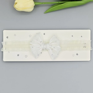 Détail d'un bandeau en dentelle blanche pour bébé avec un double nœud à paillettes
