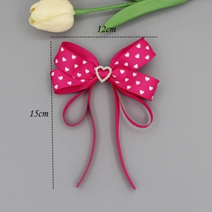 Sweet pink bow hair clip with white heart pattern and sparkling rhinestone heart detail