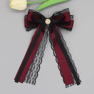 Detail of burgundy satin bow with black lace and golden floral centerpiece with faux pearls
