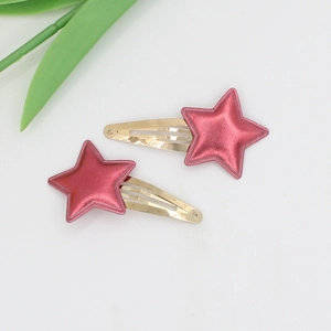 Close-up of pink star-shaped hair clips for girls with shiny metallic leather finish