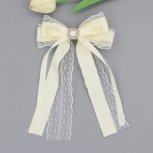 Detailed macro view of white satin bow hair clip with lace layers and pearl center
