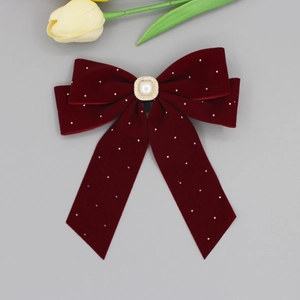 Detail view of burgundy velvet bow hair clip with small rhinestones and a square pearl center