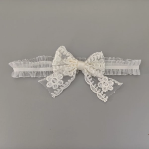 Détail du bandeau en dentelle blanche pour bébé avec broderies et nœud en satin doux