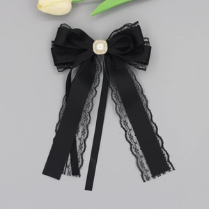 Close-up of black satin bow hair clip with delicate lace trim and pearl center ornament